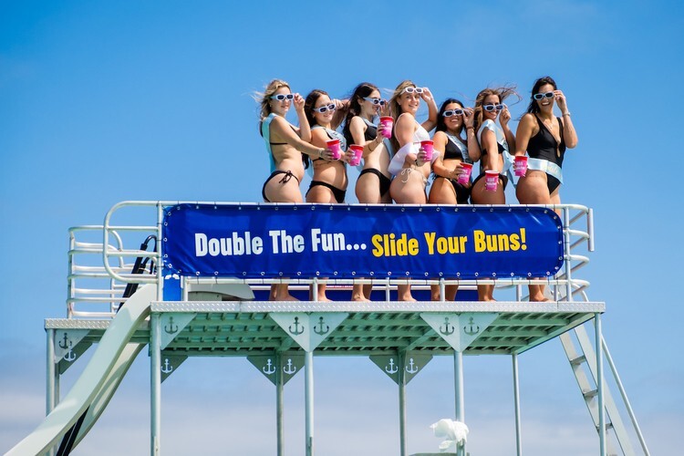 bachelorette party posing on top deck of a double-decker pontoon