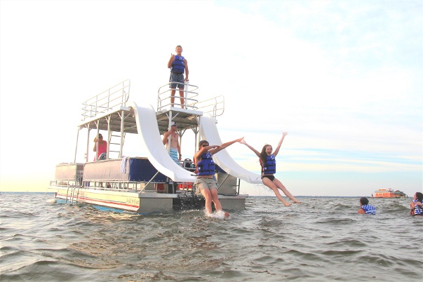 people jumping off a double decker pontoon boat