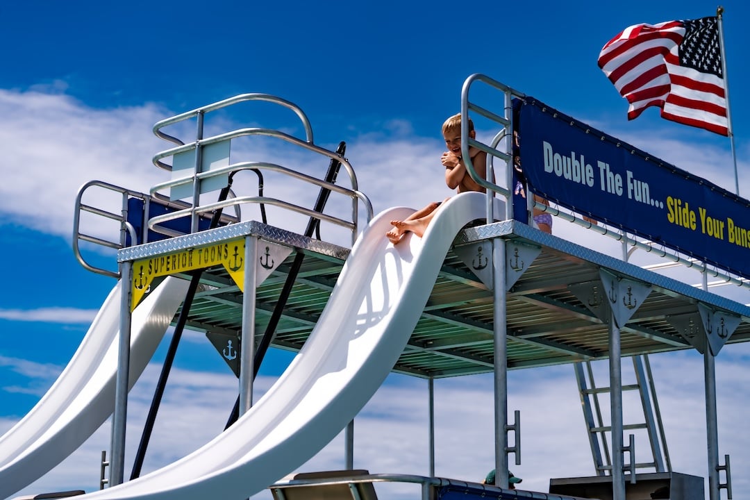 child sliding off a boat at crab island destin