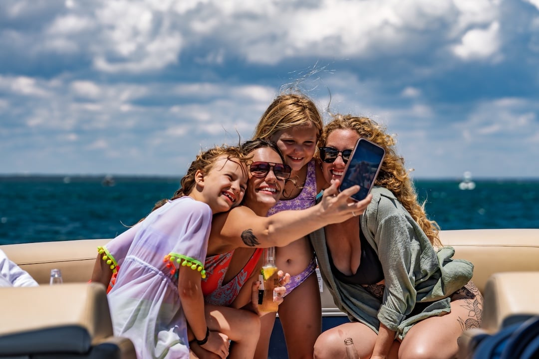 family and friends on pontoon boat taking a selfie