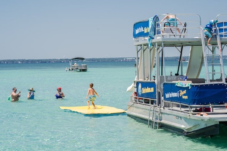 family enjoying lily pad alongside pontoon rental at crab island in destin fl