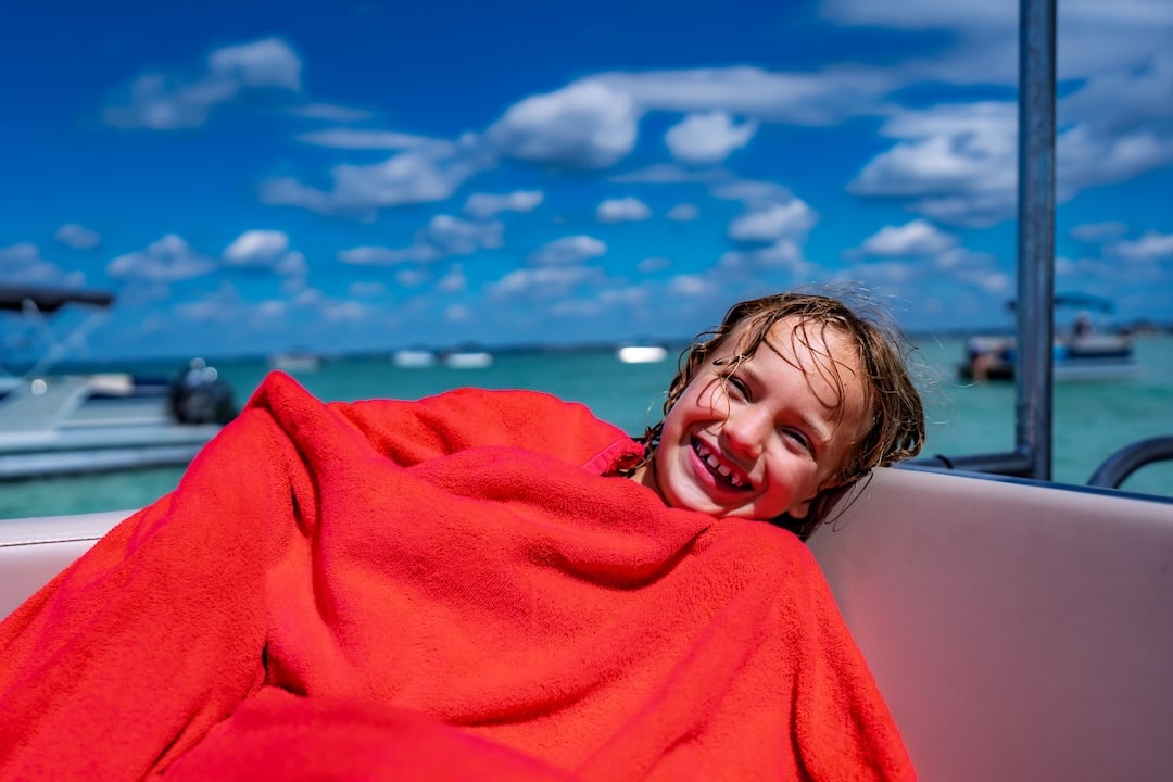 little girl wrapped up in a towel on a pontoon