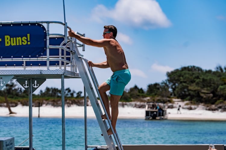 man climbing the ladder of a double decker pontoon boat at shell island PCB