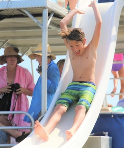 little boy sliding off a double decker pontoon boat with two waterslides in destin, florida