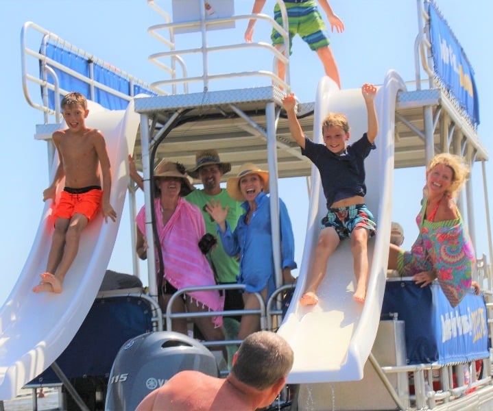 two boys sliding down a double decker pontoon boat rental in destin, florida