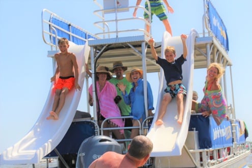 two boys sliding down a double decker pontoon boat slide by crab island in destin, florida