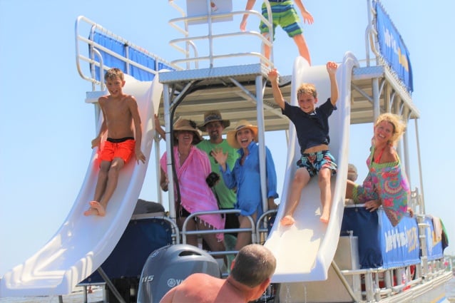 two boys sliding off of a double decker pontoon boat in destin florida