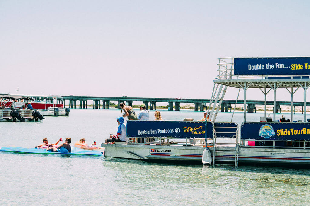 double decker pontoon boat parked at crab island with floats around it