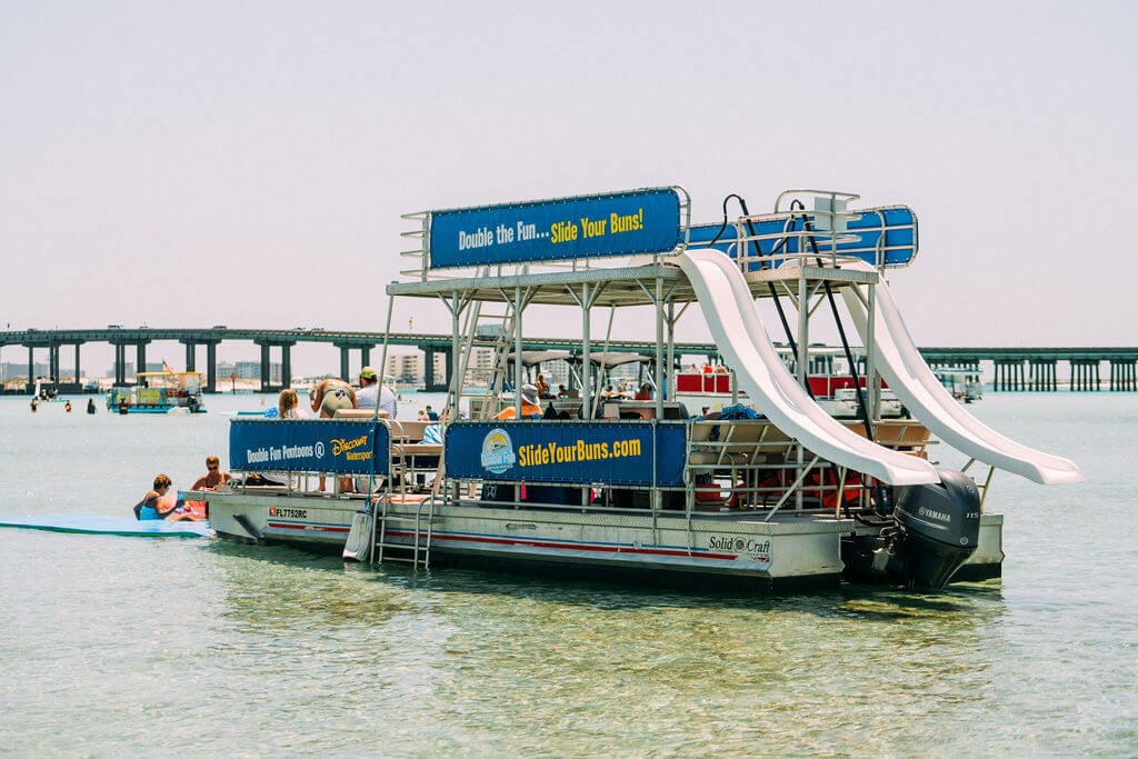double decker pontoon boat with two waterslides parked at crab island in destin, florida