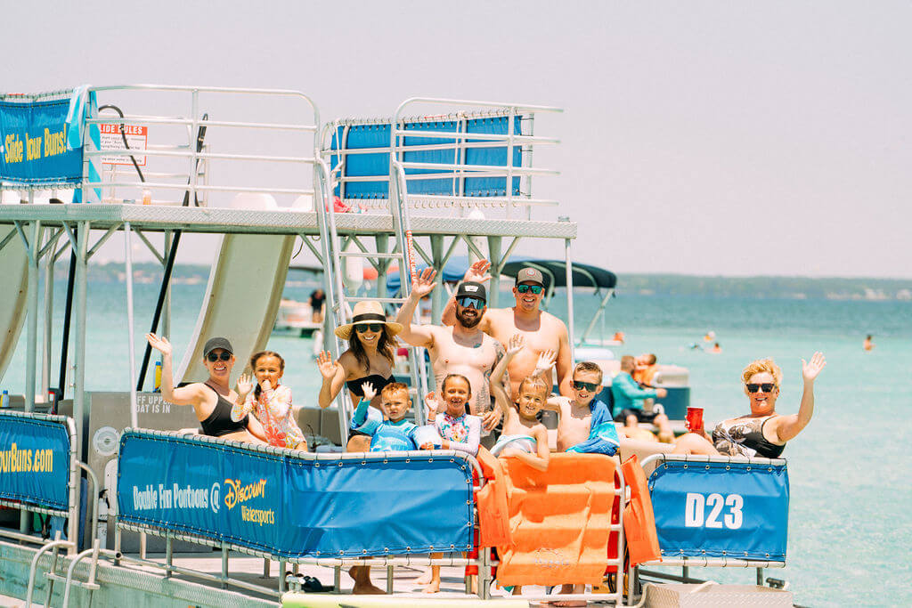 family waving on the back of a double decker pontoon boat in destin, florida