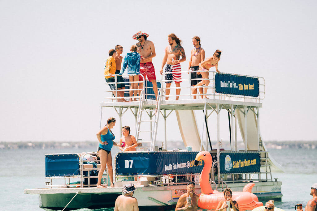 people standing on a double decker pontoon boat parked in the ocean in destin, florida