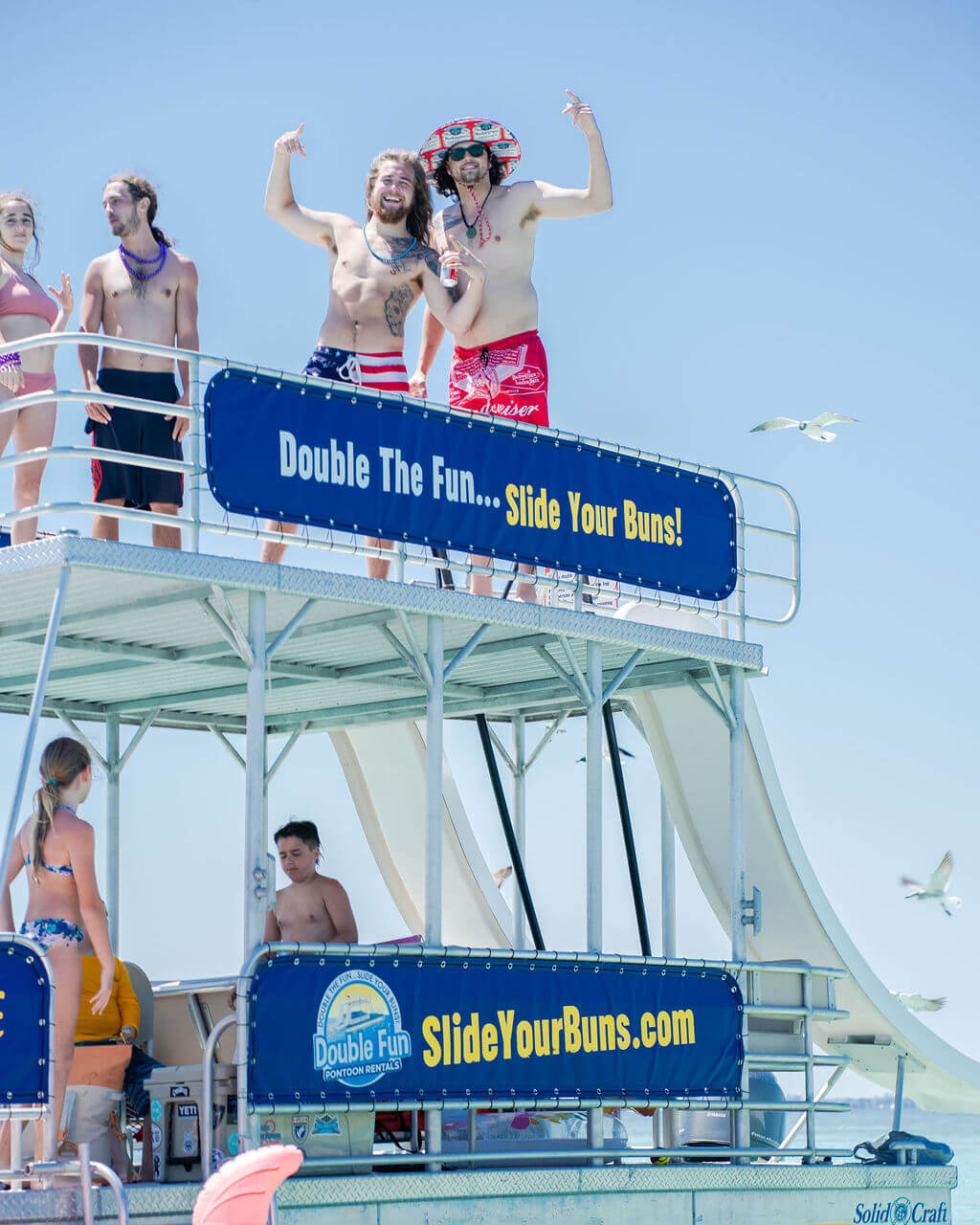 two guys standing on top of a double decker pontoon boat in destin, florida