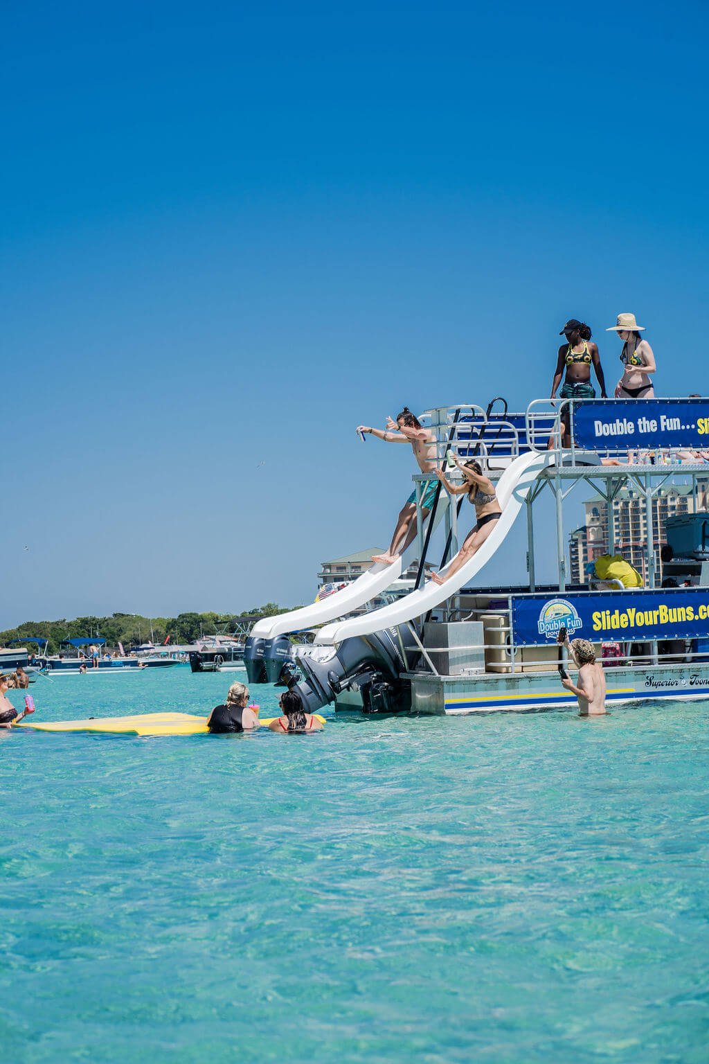 two people sliding off a double decker pontoon boat in destin, florida