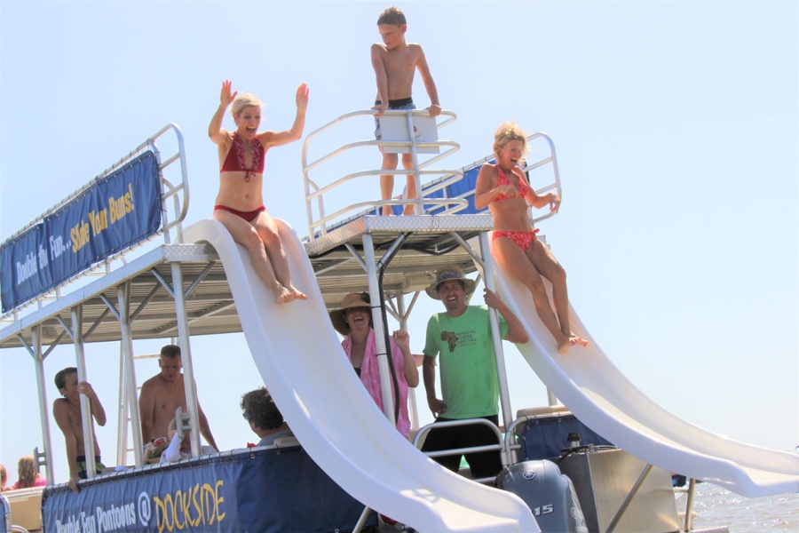 two women sliding off of two double decker pontoon boat slides