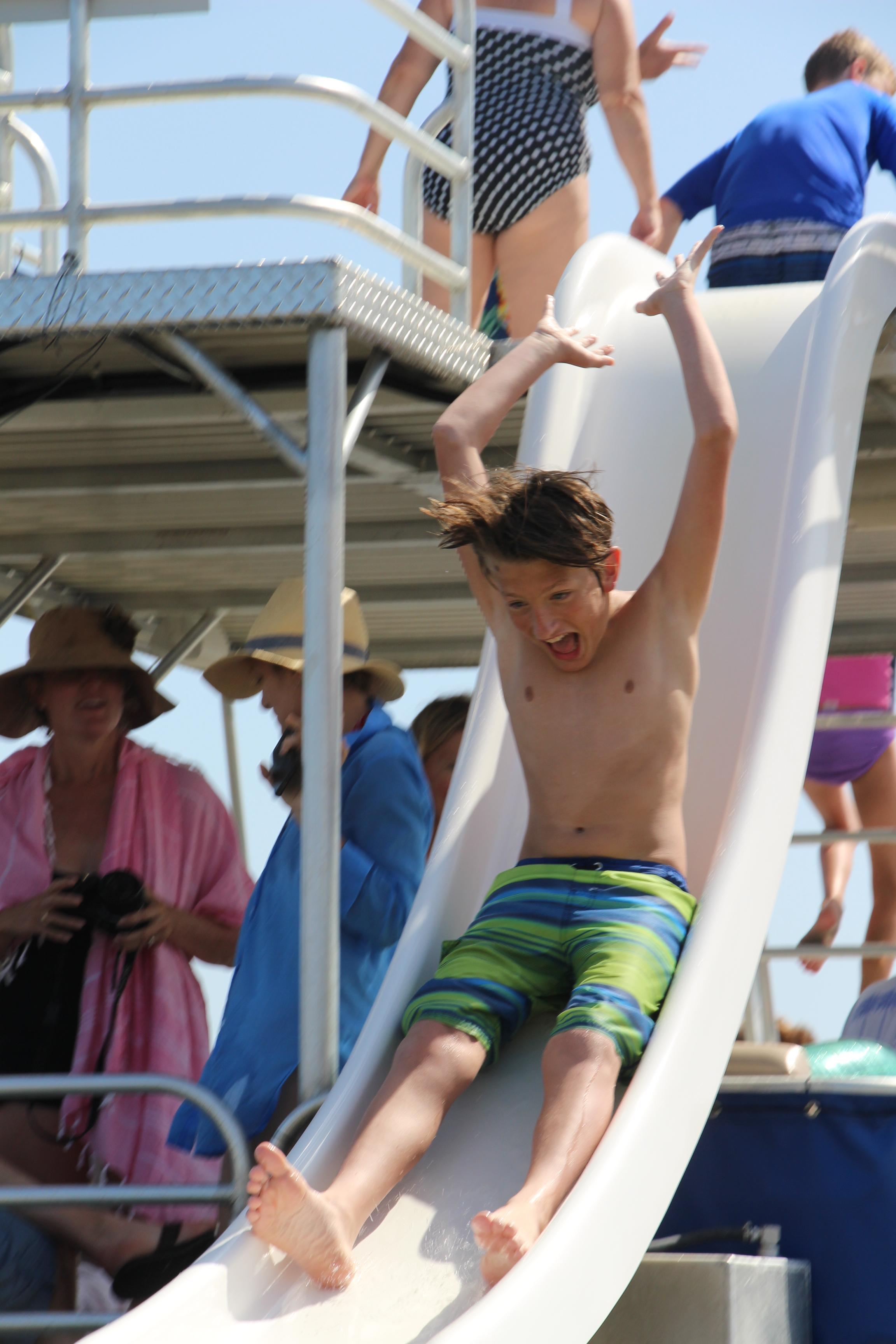 little boy sliding down a double decker pontoon boat slide