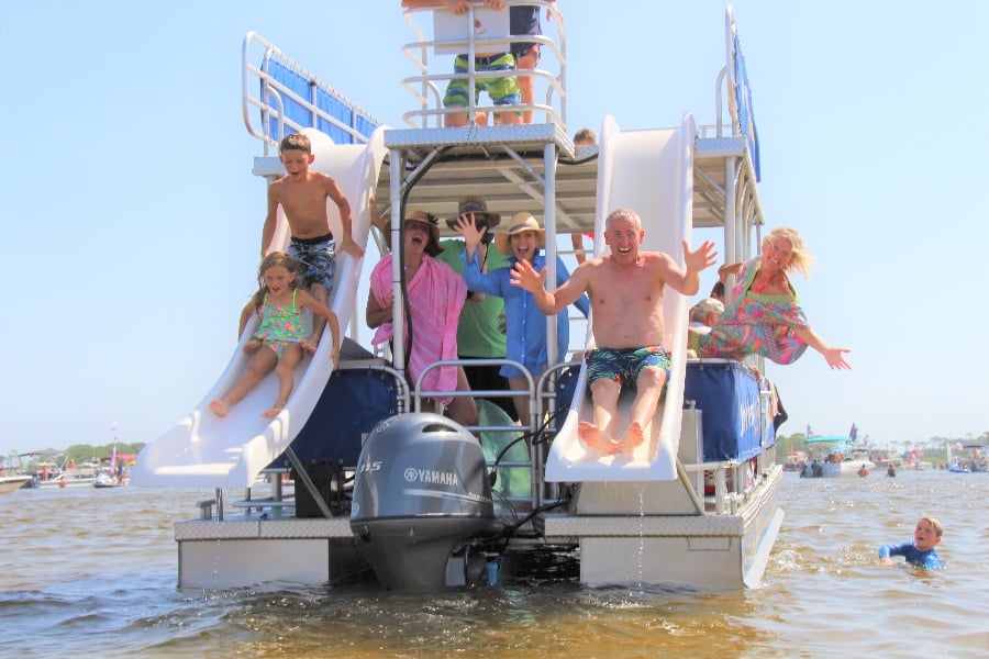 two kids and a dad sliding off of two slides on a double decker pontoon boat in destin florida