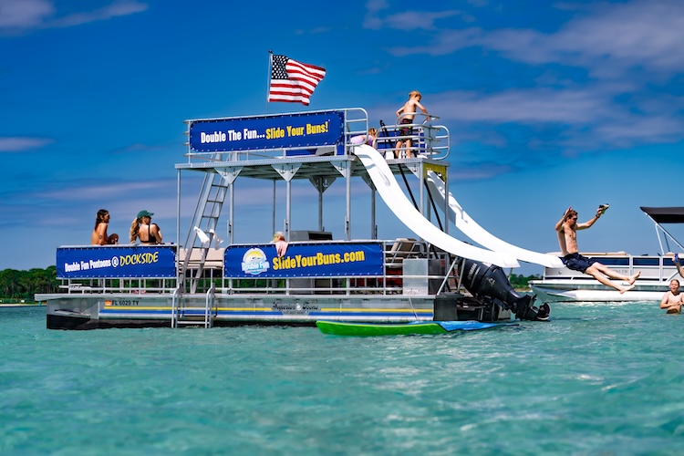man sliding into the water at crab island from double decker pontoon in destin fl with friends