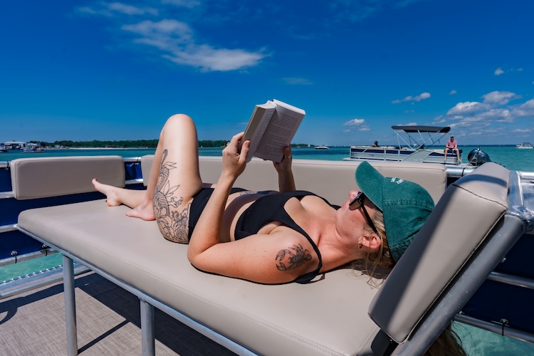 woman reading a book on a double decker pontoon rental in destin fl